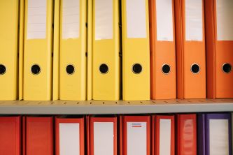 Verschiedenfarbige Bundesordner in einem Regal.