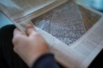 Mensch mit aufgeschlagener Zeitung in der Hand