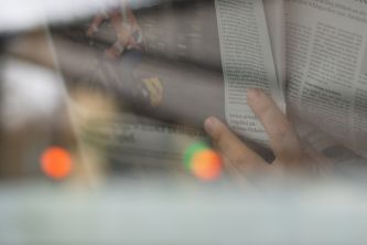 Eine Hand die eine Zeitung aufgeschlagen in der Hand hält.