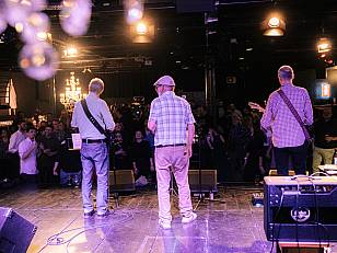 Die Austropop-Band Specknockerln mit dem Rücken zur Kamera vor dem Schlussapplaus