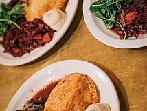 Drei Teller mit dem Hauptgang. Eine Teigtasche, rotes und grünes Gemüse, Pilze und ein klecks weisses Mousse.